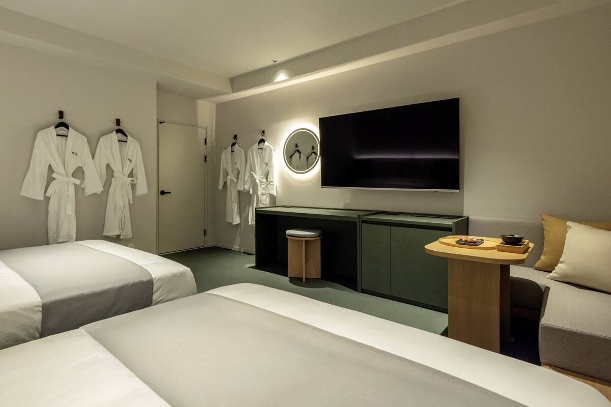 Une chambre d’hôtel avec deux lits, une télévision, une petite table avec un bol et un miroir.