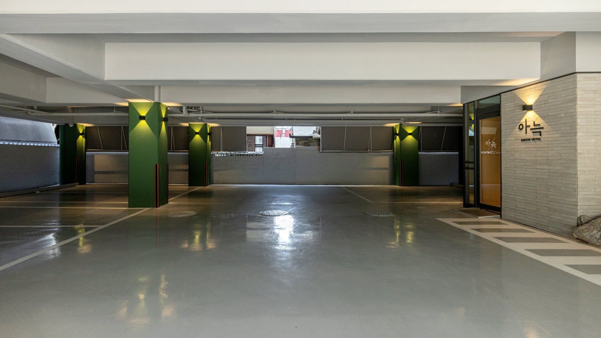 A spacious, modern hotel lobby with a clean, polished floor, green accent pillars, and a visible reception area.