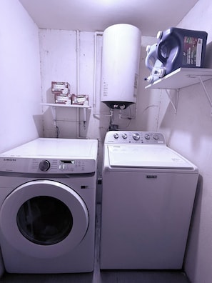 Ein Waschraum mit einer Samsung Waschmaschine, einem Maytag Trockner und einem Warmwasserbereiter auf einem Regal.