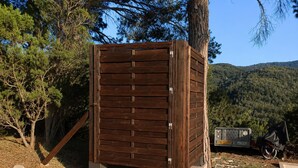 Una estructura de madera con una puerta, rodeada de árboles y un paisaje montañoso.
