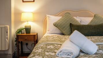 A neatly made bed with a patterned bedspread, a lamp on a bedside table, and a wall-mounted picture.
