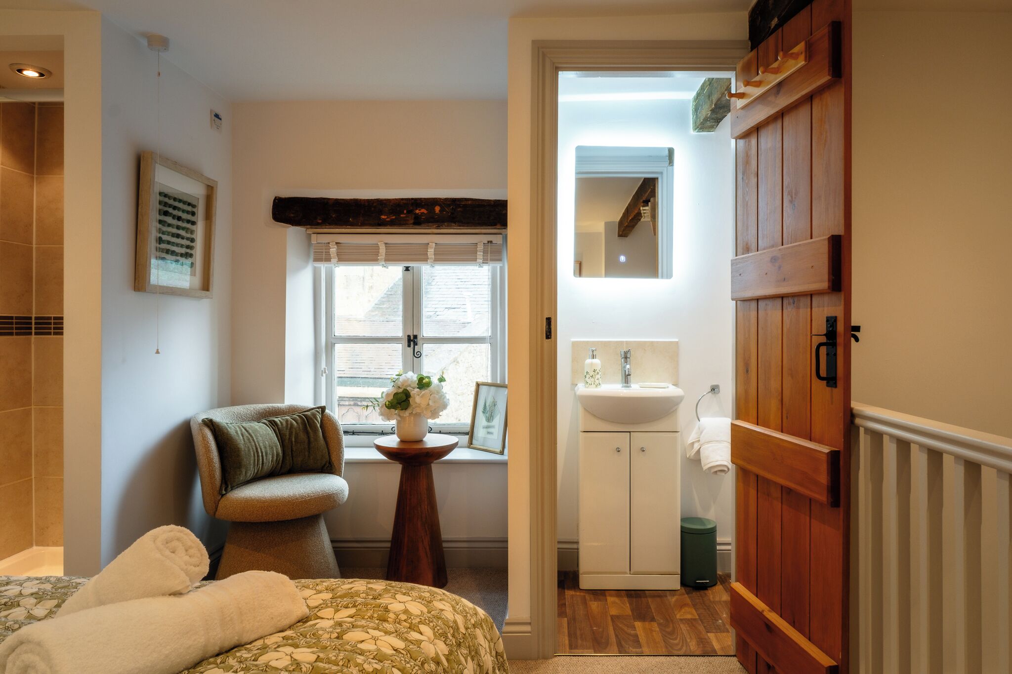 A bathroom with a wooden door, a sink, and a window with blinds.