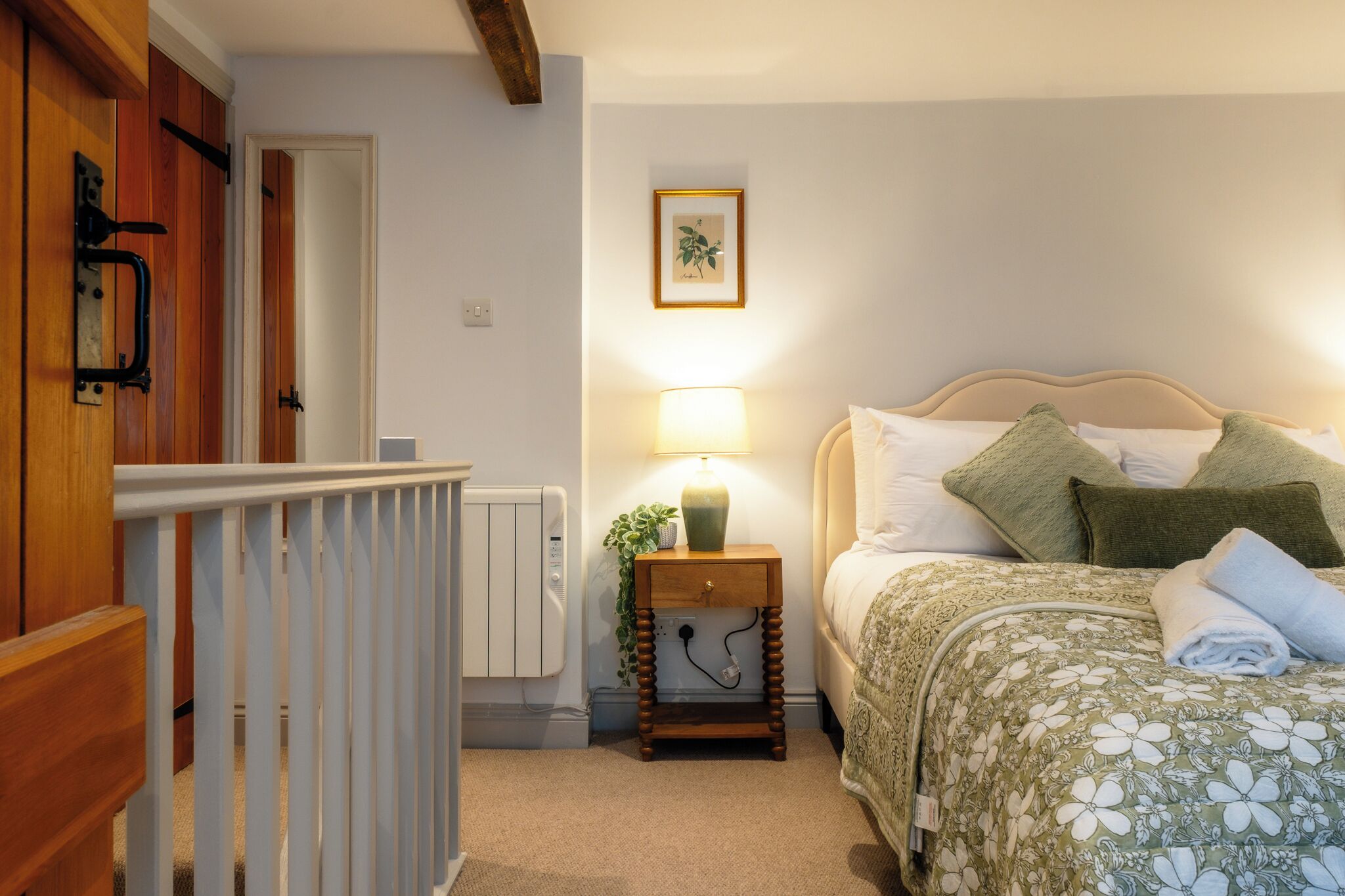 A bedroom with a bed, bedside lamp, and a framed picture on the wall.