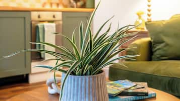 Ein runder Holztisch mit einem Blumentopf, ein grünes Sofa und eine Lampe in einem Wohnbereich.