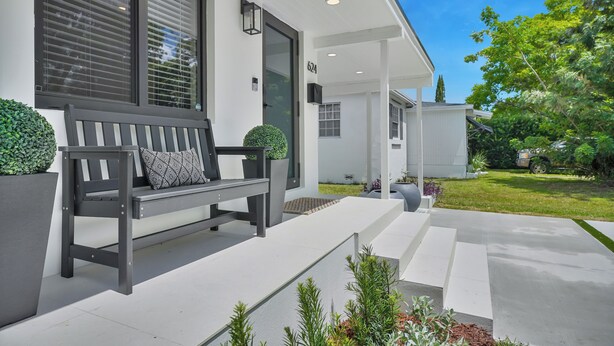 A modern house with a bench outside, a well-maintained lawn, and a clear sky. - Airport Casita •FULL PRIVACY• 5min Airport •2min Walk to IHOP• remodeled 2026 (Miami Springs)