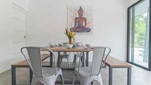 A dining area with a table, chairs, and a Buddha painting. - Wantana villa Sawaree villa 1 V308 (Chang Wat Surat Thani)