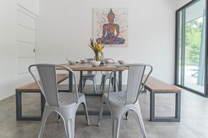 A dining area with a table, chairs, and a Buddha painting. - Wantana villa Sawaree villa 1 V308 (Chang Wat Surat Thani)