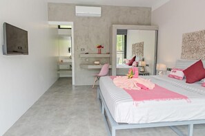 Een slaapkamer met een bed, een stoel, een kaptafel, een spiegel en een wandairconditioner.