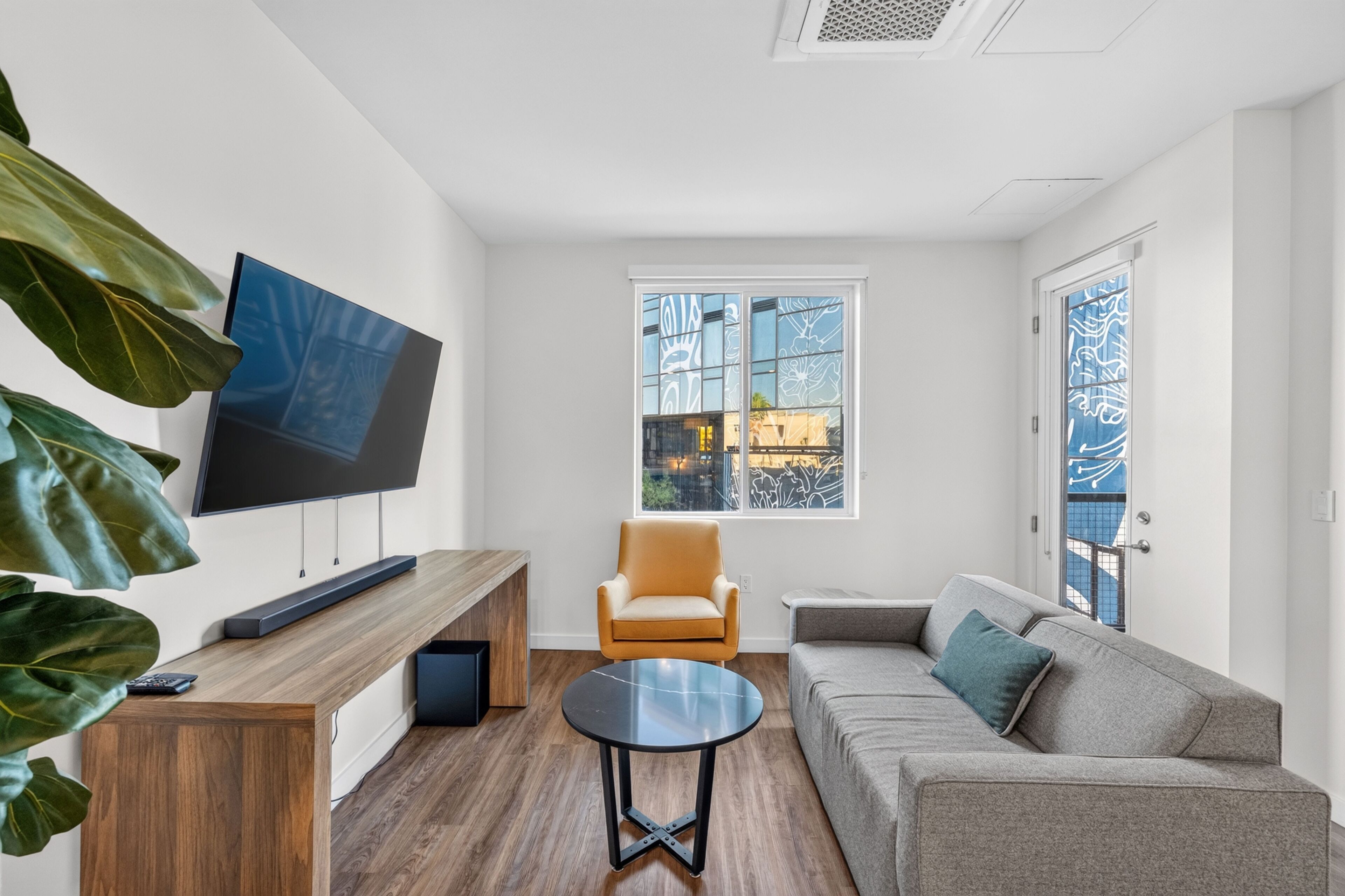 Una sala de estar moderna con televisor, sofá, mesa de centro y un sillón.