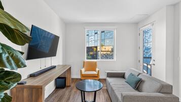 Una sala de estar moderna con televisor, sofá, mesa de centro y un sillón.