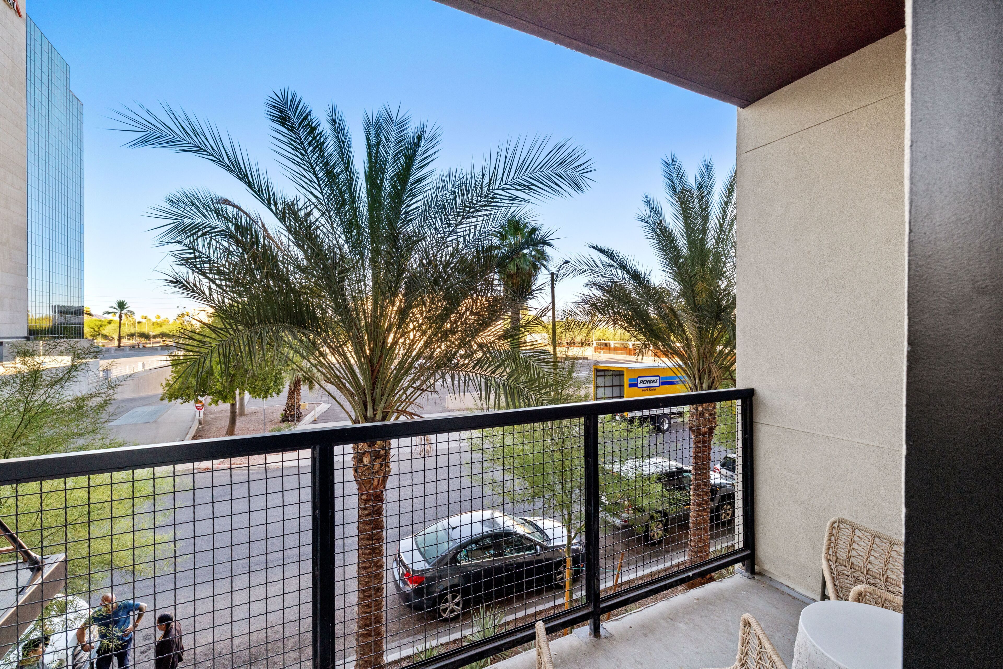 A balcony with a view of palm trees, a street, and a building.