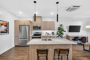 Una cocina moderna con una isla central, electrodomésticos de acero inoxidable y un televisor de pantalla plana montado en la pared.