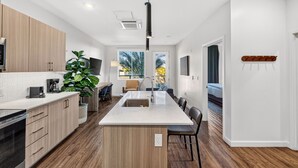 Una cocina moderna con una isla central, armarios de madera y una planta grande en maceta.