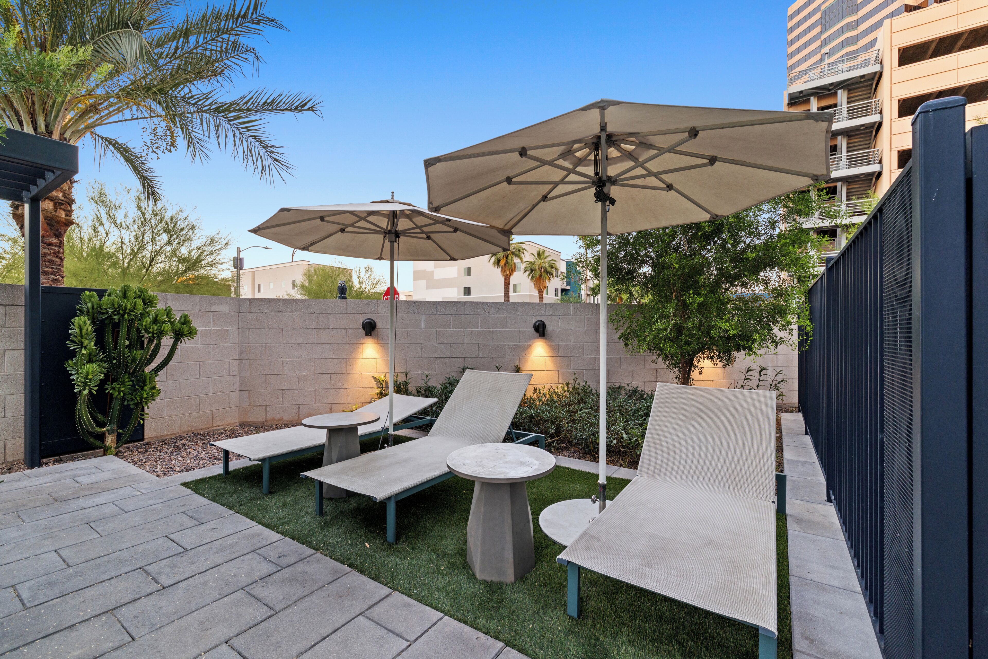 A patio with lounge chairs, a round table, and two umbrellas.