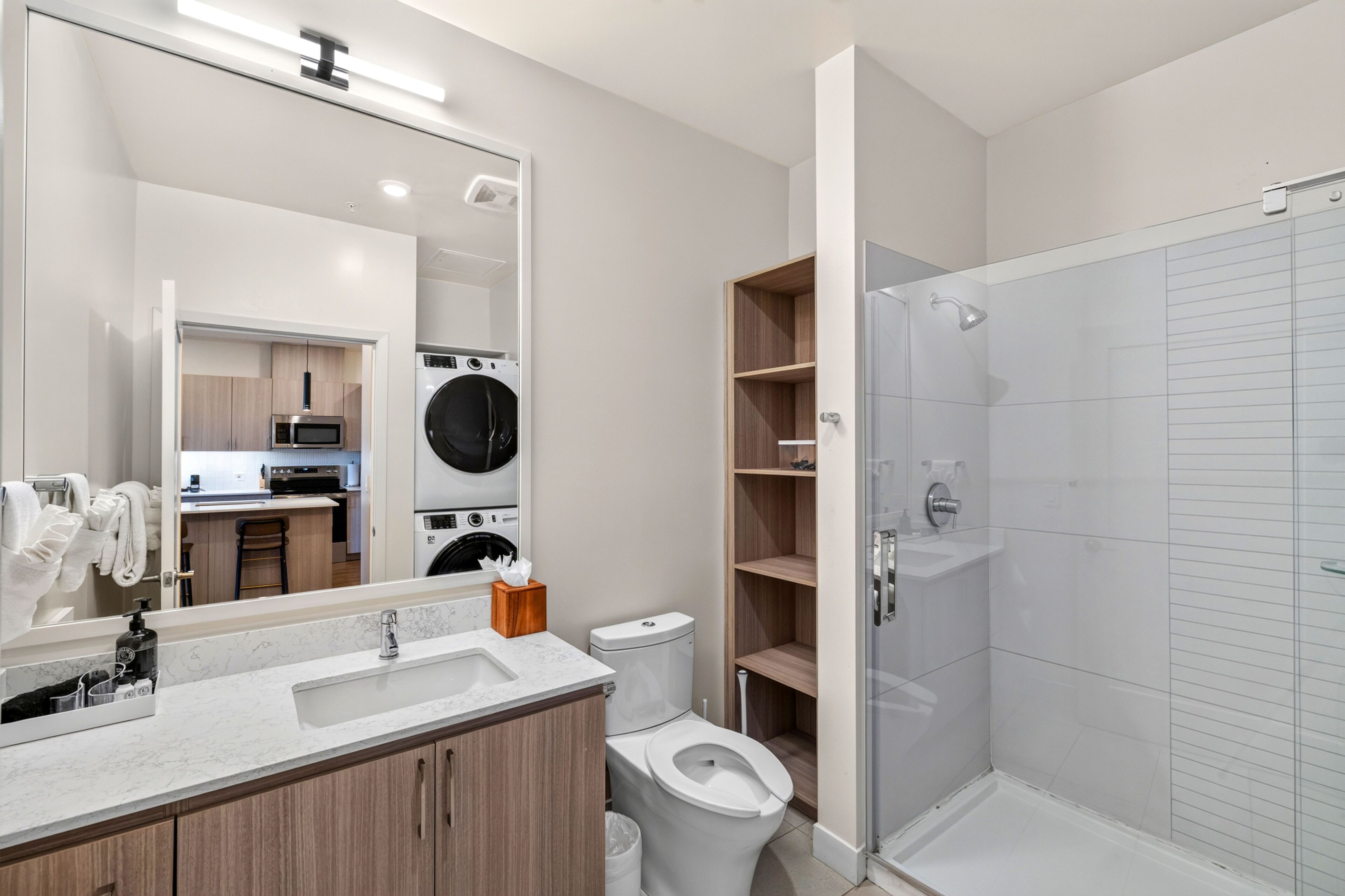 Ein modernes Badezimmer mit Dusche, Toilette, Waschbecken und einer integrierten Küchenzeile.