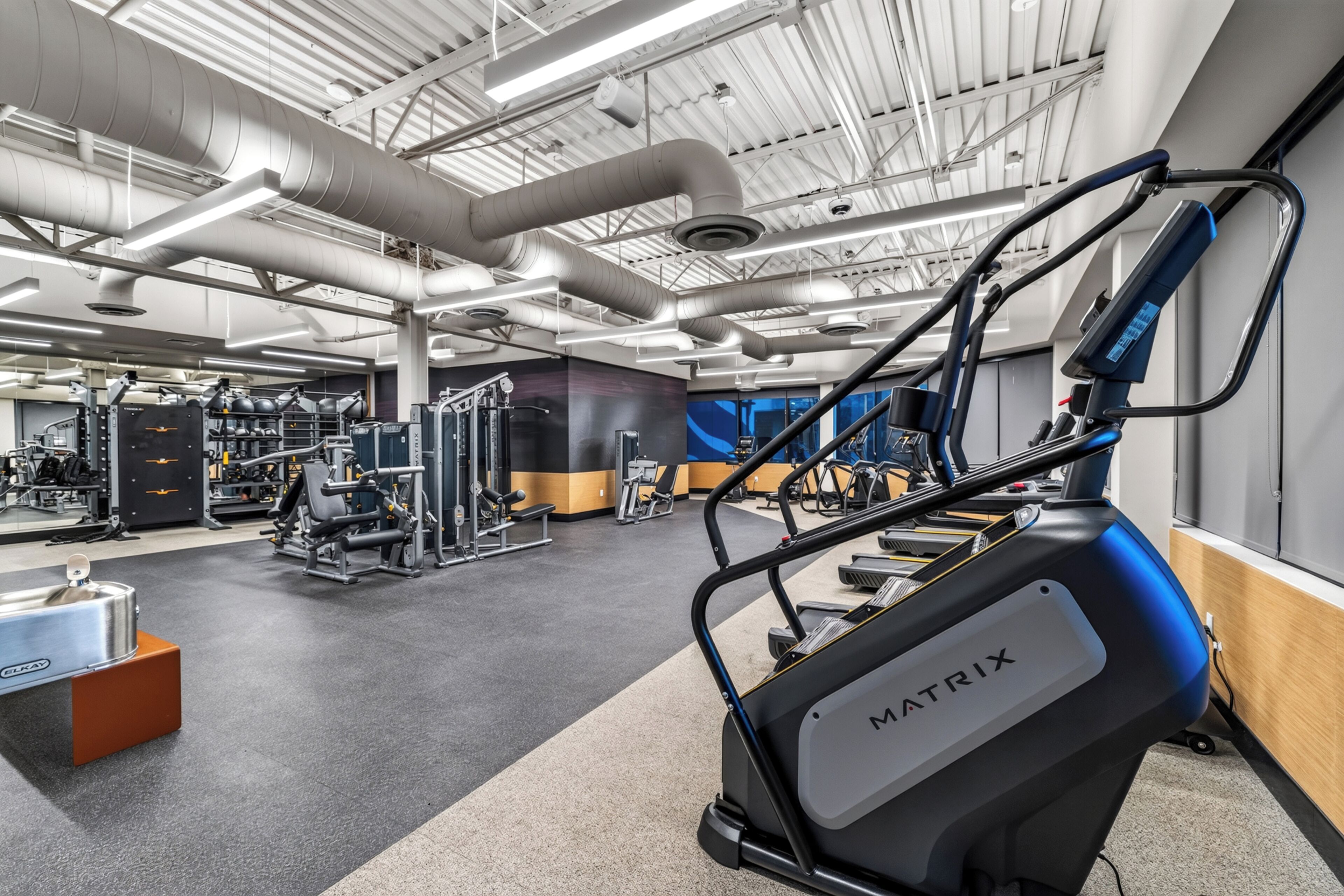 Une salle de sport équipée de divers appareils d’exercice, notamment un tapis de course et des appareils de musculation.
