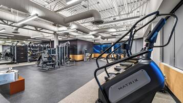 Une salle de sport équipée de divers appareils d’exercice, notamment un tapis de course et des appareils de musculation.