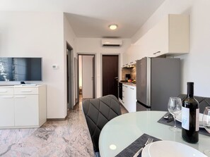 A modern kitchen with a TV, dining table, and chairs. - Apartment Teide by Interhome (Pula)