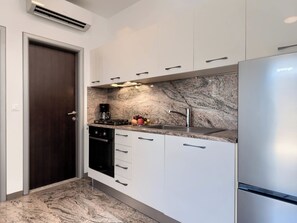 A modern kitchen with white cabinets, a marble backsplash, a stainless steel refrigerator, and a built-in oven. - Apartment Teide by Interhome (Pula)