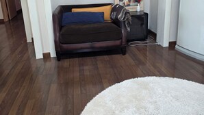 Una habitación con un sofá de cuero marrón, un felpudo blanco mullido y un cuadro en la pared.