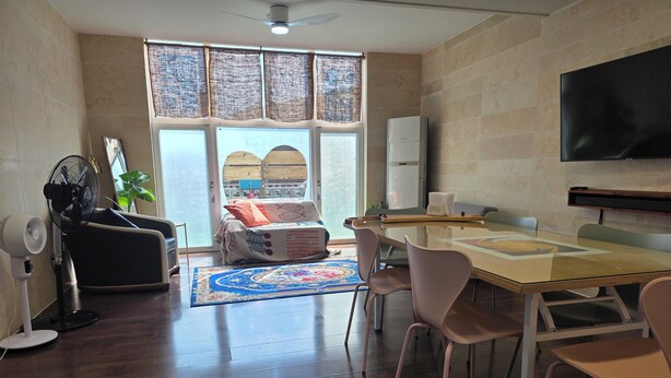 A modern living room with a glass table, comfortable seating, a large window, and a flat-screen TV. - MurMum 2 (Chilgok)