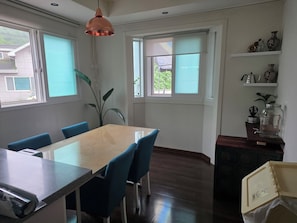 A dining area with a table, chairs, and a hanging light fixture.