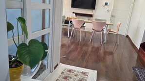 A modern interior with a dining area, a flat-screen TV mounted on the wall, and a potted plant by the window. - MurMum 2 (Chilgok)