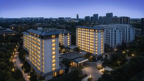 Un moderno complejo hotelero con varias torres altas, un patio cuidado y un horizonte urbano al fondo.