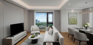 A modern living room with a flat-screen TV, a sofa, a dining area with a table set for two, and a large window with a city view. - FRASER RESIDENCE WUZHEN (Jiaxing)