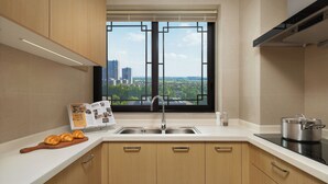Una cocina moderna con armarios de madera, un lavamanos de acero inoxidable y un ventanal con vistas a la ciudad.