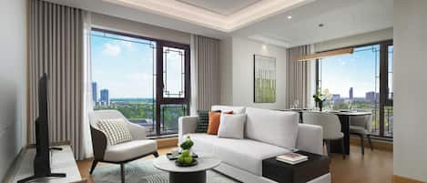 A modern living room with a sofa, armchair, coffee table, and a flat-screen TV.