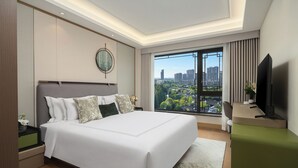 Una habitación de hotel moderna con una cama grande, un escritorio, un televisor y vistas a la ciudad.