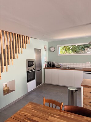 A modern kitchen with wooden slats, stainless appliances, and a view of greenery outside. - Beaulieu Le 15 Vacation Rental – Ambleteuse (sleeps 15) (Ambleteuse)
