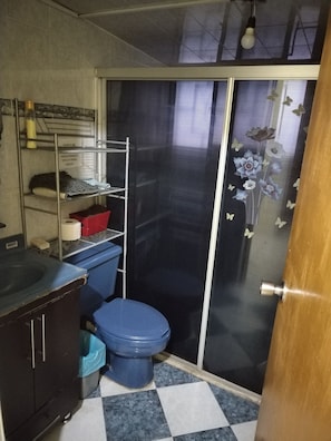A compact bathroom with a toilet, a sink, and a shelving unit with toiletries. - Yellow House Near the Historic Center (Durango)