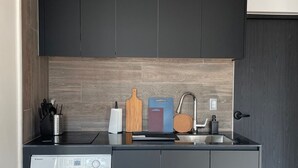 Una cocina compacta con lavadora integrada, muebles oscuros y salpicadero de madera.