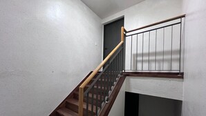 Una escalera de madera con barandillas metálicas que lleva a un rellano con una puerta.