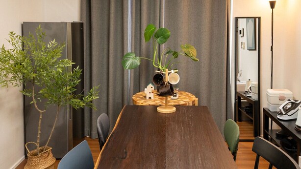 Un comedor con una mesa de madera, sillas, una planta en maceta y un pequeño adorno para el hogar.