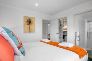 Een hotelkamer met een bed, een douche en een inloopkast.