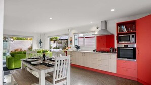 Cocina moderna con comedor, muebles de cocina color rojo y vistas al exterior.