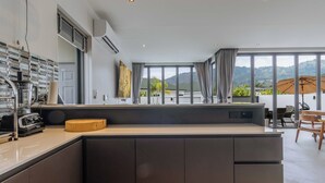 Cozinha moderna com uma ilha grande, área de refeições com mesa e cadeiras, e vista para montanhas através de amplas janelas.