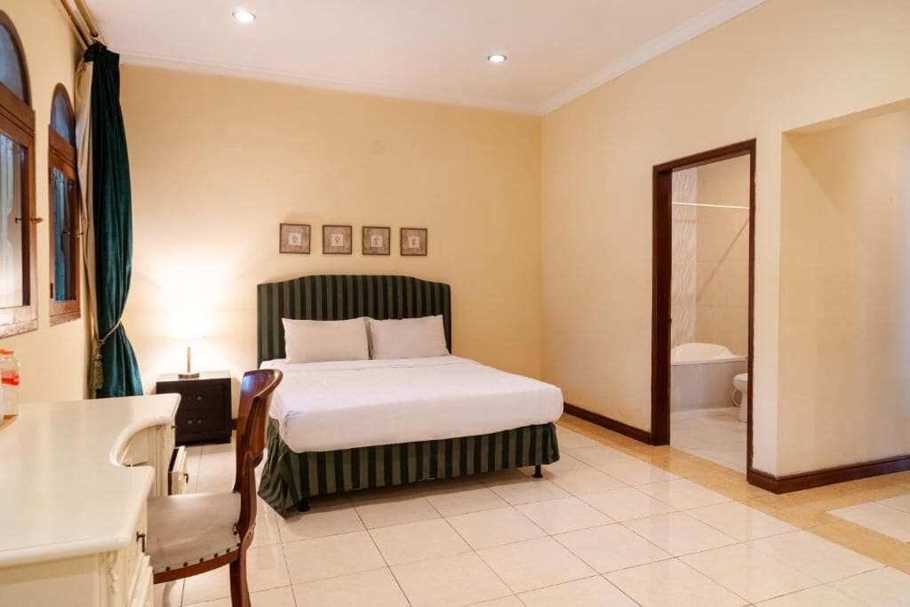 Una camera d'albergo con un letto, una sedia, una scrivania e un bagno.