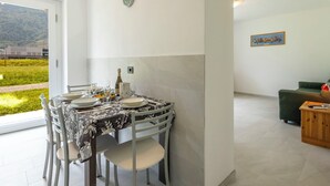 Uma sala de jantar com mesa posta para quatro pessoas, um sofá verde e um quadro na parede.