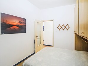 A bedroom with a bed, a door, a wall-mounted picture, and a wooden wardrobe. - Ardesia by Interhome (Lavagna)