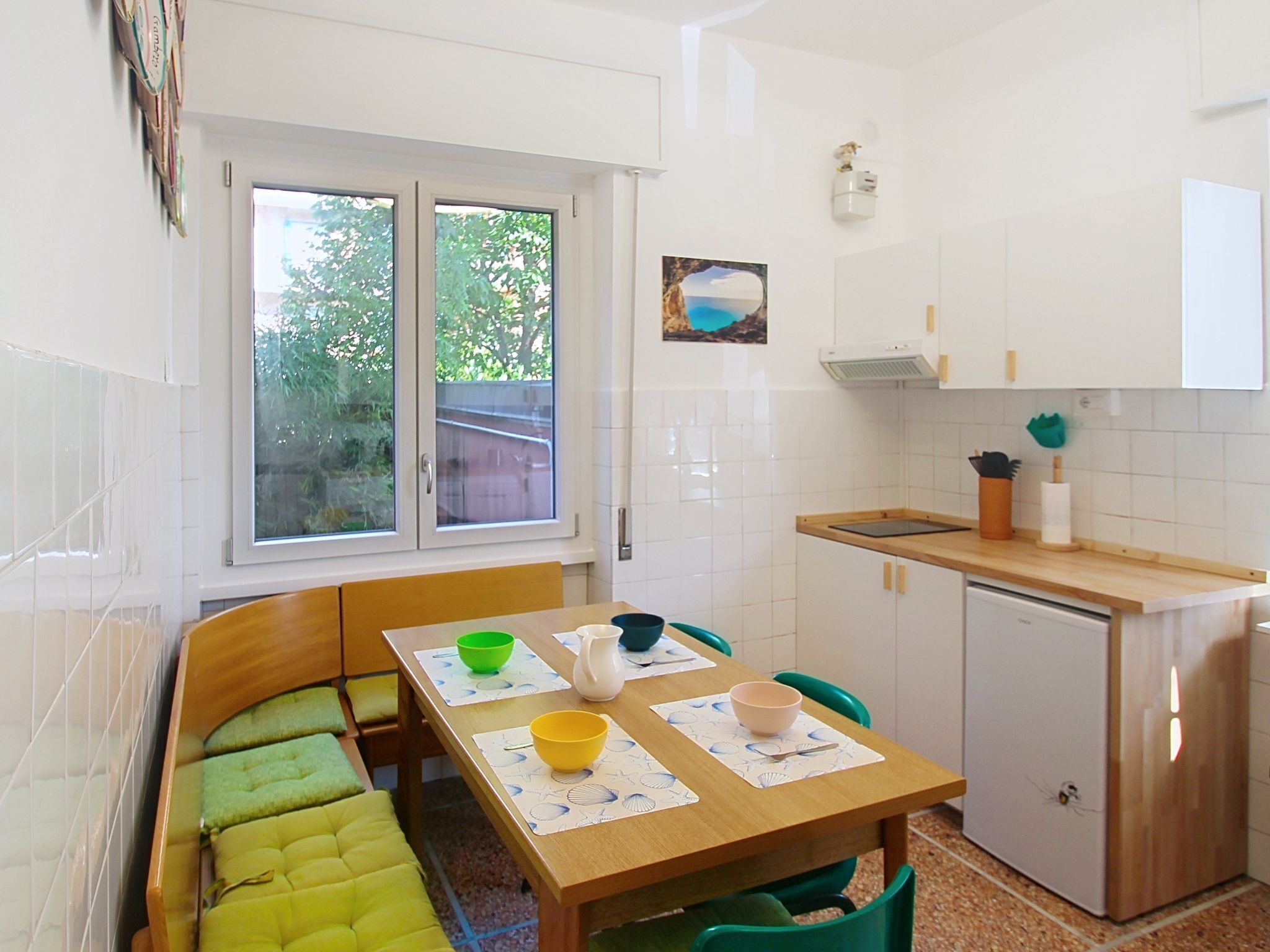 A compact kitchen with a dining table, chairs, and a small refrigerator.