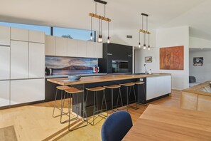 Eine moderne Küche mit einer großen Kochinsel, Barhocker und Pendelleuchten.