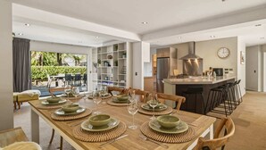 A modern dining area with a long wooden table set for six, surrounded by chairs.