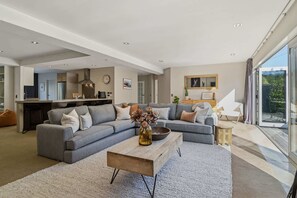Ein modernes Wohnzimmer mit einer grauen Eckcouch, einem Holztisch und einem großen Fenster.