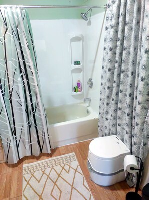 Ein Badezimmer mit Badewanne, Dusche, Toilette und einem kleinen Ablagebereich für Toilettenartikel.