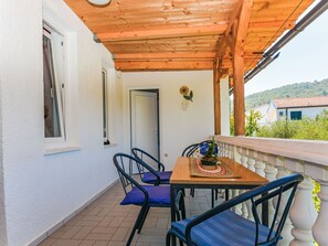 A balcony with a wooden ceiling, a table with chairs, and a view of a green landscape. - Apartment Jako by Interhome (Trogir/Slatine)