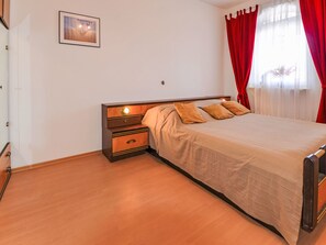 A bedroom with a bed, nightstands, a dresser, a framed picture on the wall, and red curtains. - Apartment Jako by Interhome (Trogir/Slatine)
